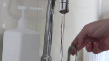 Mutfak lavabosunun kapağı suyu kapatıyor. Erkeklerin elleri bir sürü bulaşığı yeşil bir süngerle yıkadı ve musluğu kapattı. Püskürt. Düşen su damlaları. Kapat.