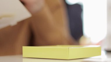 Tanınmayan bir kadın küçük sarı bir karton kutuyu katlıyor. Kağıttan karton kutu üretimi. Ambalaj imalat şirketi. Yaratıcı bir derste kağıt işçiliği yapan ellerin yakın çekimi..