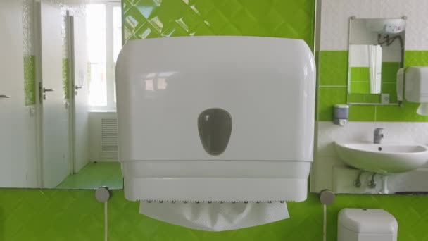 壁にペーパータオルのためのディスペンサー 公衆トイレの白いプラスチック製の箱の中の白い組織 ぬれた手と顔を拭くために紙の一部を引き出します 医療と予防の概念 — ストック動画