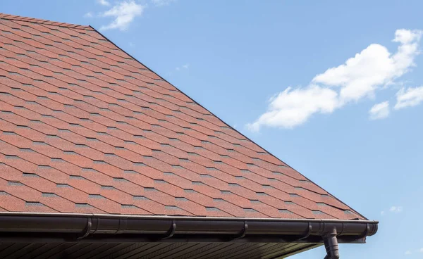青い空に対して赤い帯状の新しい屋根 高品質の写真 家の屋根の上のタイル 屋根の製造とメンテナンスを宣伝するために使用します 発見されたテクスチャ 手頃な屋根 — ストック写真