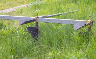 Tarımsal manuel metal tarla tarlasında. Ekmeden önce toprağı sürüyorum. Yakın plan. Kırsalda patates sürme envanteri. Saban, yoğun toprağı sürmek ve bakir toprağı işlemek için kullanılan bir araçtır.