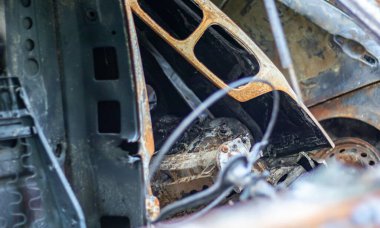 Araba tamamen yangın tarafından tahrip edildi. Yol kenarında terk edilmiş, yanmış ve paslı bir araba. Arabalar otoparkta yanıyordu. Rusya 'nın Ukrayna' ya karşı savaşı. Arabalarda şarapnel ve kurşun delikleri var.