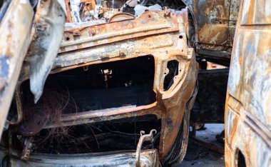 Araba tamamen yangın tarafından tahrip edildi. Yol kenarında terk edilmiş, yanmış ve paslı bir araba. Arabalar otoparkta yanıyordu. Rusya 'nın Ukrayna' ya karşı savaşı. Arabalarda şarapnel ve kurşun delikleri var.