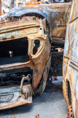 Araba tamamen yangın tarafından tahrip edildi. Yol kenarında terk edilmiş, yanmış ve paslı bir araba. Arabalar otoparkta yanıyordu. Rusya 'nın Ukrayna' ya karşı savaşı. Arabalarda şarapnel ve kurşun delikleri var.