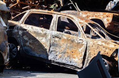 Araba tamamen yangın tarafından tahrip edildi. Yol kenarında terk edilmiş, yanmış ve paslı bir araba. Arabalar otoparkta yanıyordu. Rusya 'nın Ukrayna' ya karşı savaşı. Arabalarda şarapnel ve kurşun delikleri var.