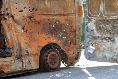 Kurşunlarla delik deşik edilmiş yanmış bir araba cesedi. Rusya 'nın Ukrayna' ya karşı savaşı. Tahliye sırasında Rus askeri arabası tarafından vurularak öldürüldü. Mermi izleri ve kovan parçaları.