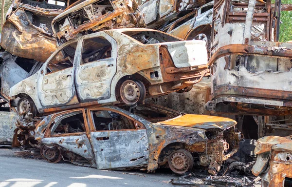 A view of burnt-out cars after rocket attacks by the Russian military. War of Russia against Ukraine. Civil vehicle after the fire. Cemetery of cars in the city of Irpin. Rusty pile of metal
