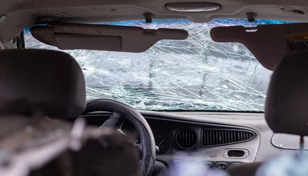 Damaged car window after an accident. Broken windshield as a result of an accident, inside view. Cabin interior details, view from the cab. Safe movement. Broken windshield. Glass crack and damage