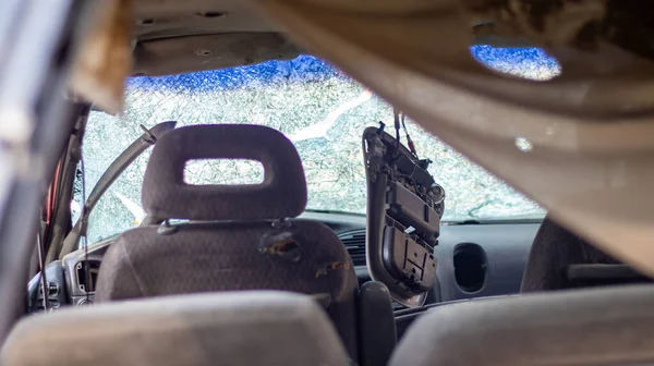 Close-up of a car with a broken windshield after a fatal crash. Consequence of a fatal car accident. Reckless dangerous driving. View of the interior of the car from the rear window