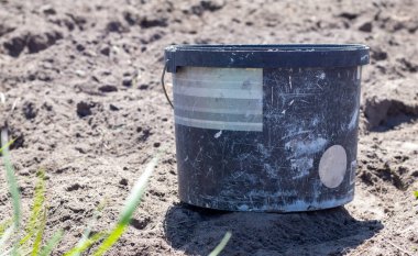 Plastik kirli bahçe kovası, gevşek zeminde sebze bahçesinin sapı olan konteynır. Bahçe malzemeleri. Bahçede güneşli bir gün