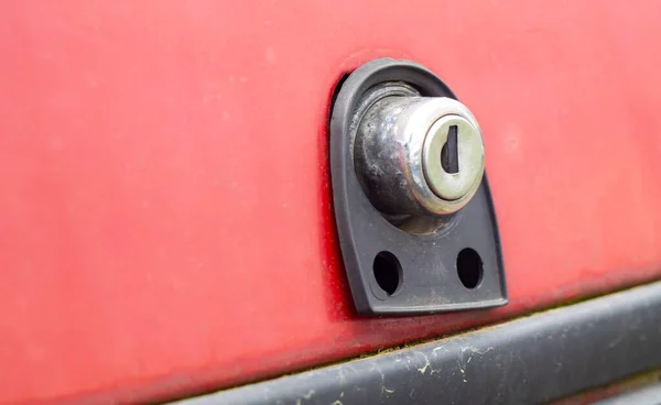 Old car trunk lock. Trunk lock details. Close-up of a handle to open the back door of a vintage red car.