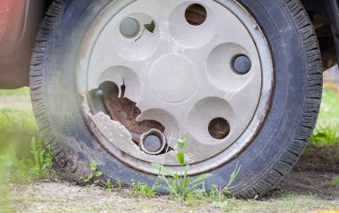 Çamur ve kir içinde yıpranmış araba tekerleği. Paslı terk edilmiş araba otoparkta. Eski bir arabanın restorasyonu. Lastik patladı. Klasik kırmızı araba şapkalı klasik tekerlek.