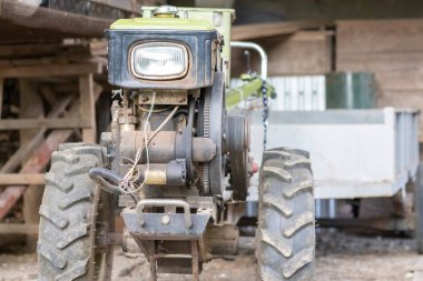 Typical heavy diesel walking tractor with trailer. Agricultural transport equipment of the countryside. Portable agricultural equipment, walking minitractor. The start system is mechanical and manual