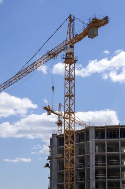 Güneşli bir günde bulutlu bir gökyüzüne karşı çalışan bir vinç. Kentsel gelişim ve inşaat kavramı. Endüstriyel geçmiş. Turna mühendisliği, inşaat endüstrisi aracı