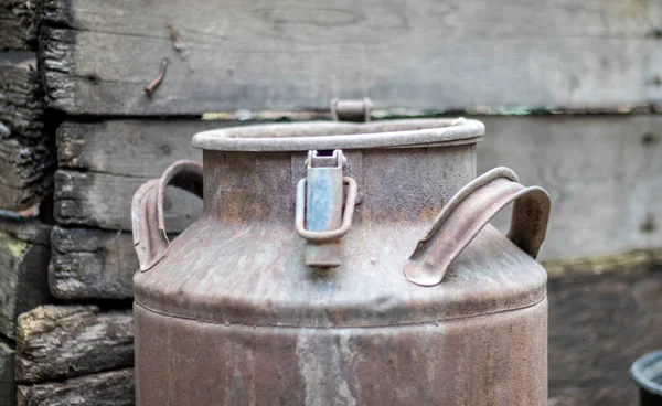 One old rusty metal can in the countryside. Container for transporting liquids, milk or liquid fuels with multiple handles. Milk bank of a cylindrical form with a wide mouth. Bottle with sealed cap