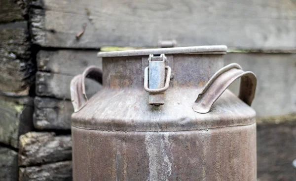 One old rusty metal can in the countryside. Container for transporting liquids, milk or liquid fuels with multiple handles. Milk bank of a cylindrical form with a wide mouth. Bottle with sealed cap