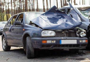 Broken car after a traffic accident in the parking lot of a repair station. Car body damage workshop outdoors. Sale of insurance cars. Accident on the street, car after a collision in the city