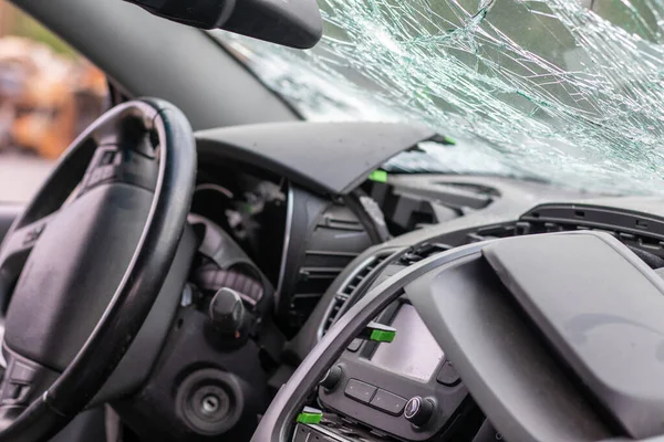 Damaged car window after an accident. Broken windshield as a result of an accident, inside view. Cabin interior details, view from the cab. Safe movement. Broken windshield. Glass crack and damage