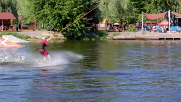 一个有经验的守夜人跳起来 运动员在湖上冲浪时 在缆绳尾流公园 在水上公园表演特技表演的极限运动者 Ukraine Kyiv August 2022 — 图库视频影像