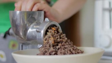 Tebdili kıyafet bir kadın ev mutfağında et pişirir. Manüel mekanik et öğütücüsünde kıyma. Taze haşlanmış et, eski metal öğütücüde öğütülür. Mutfakta yakın plan.