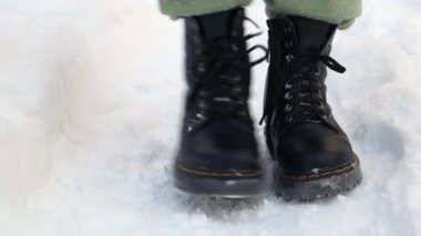Kışın siyah çizmeli donmuş bir adamın ön görüntüsü. Kışın evin girişinde botlarından karları silkelemek. Ayakkabıdan kar silkeleniyor, kışın şiddetli kar yağıyor..