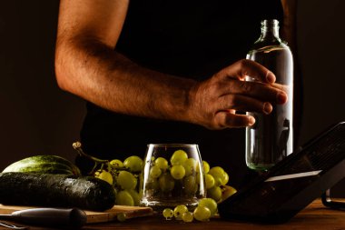 Adam salatalık ve üzümle kokteyl yapıyor.