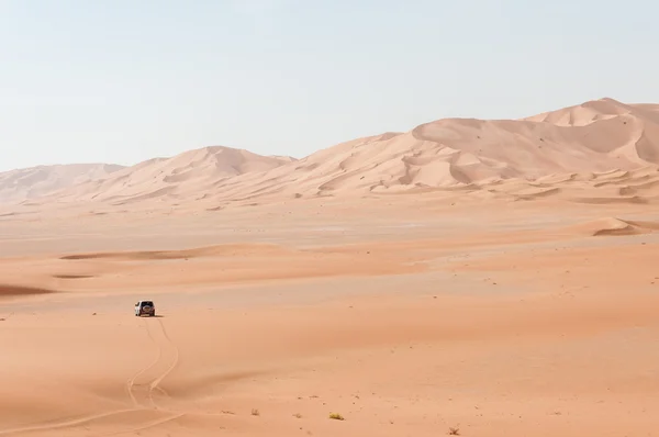 Auto mezi písečnými dunami v Ománu poušti (Omán) — Stock fotografie