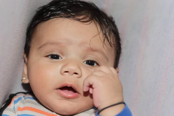 Close-up of An indian little newborn innocent baby surprised to look at the camera with white background