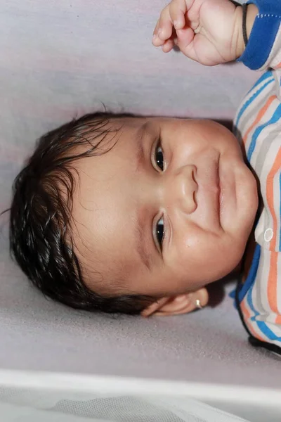 Küçük, Asyalı, masum bir çocuğun kapalı mekânda kameraya bakıp gülümsediği yakın plan.