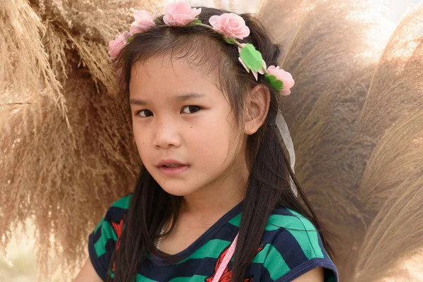 Sıcak tonlarda pembe bir saç bandı takan Asyalı bir kızın portresi.