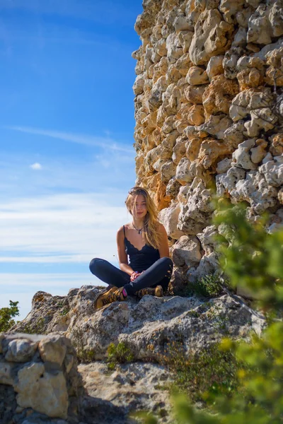 Chica turística sentada cerca de una antigua torre de piedra — Foto de Stock