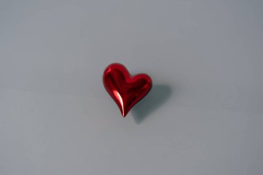 Gri cam arka planda izole edilmiş kırmızı parlak kalp. Metin için alanı kopyala.