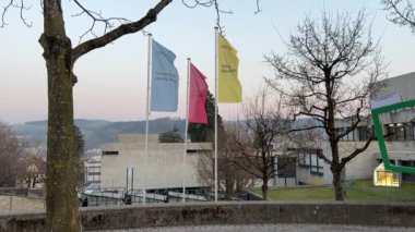 St. Gallen 26.03.2022 - Huzurevinden güzel akşamları binaları olan HSG Üniversitesi 'nin üç bayrağına kadar manzara. Bayraklar üzerindeki slogan: Yarın yavaş çekimde başlıyor