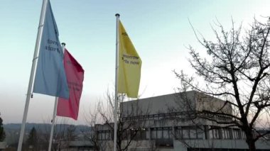 St. Gallen 26.03.2022 - Güzel bir akşamda HSG Üniversitesi 'nin bayraklarını binalar ve çıplak ağaçlarla çevirip kapatın. Bayraklar üzerindeki slogan: Yarın şimdi başlıyor
