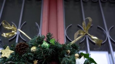 Beyaz noktalı şık bir çelenk, altın yıldızlar ve dışarıda kırmızı evin kapısında Noel ağaçları..