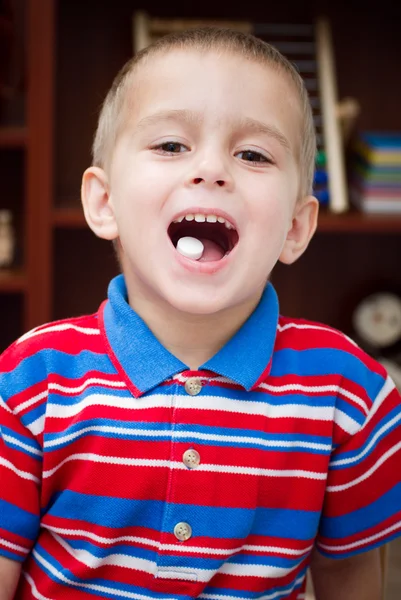 Giovane ragazzo mostrando una capsula sulla lingua — Foto Stock