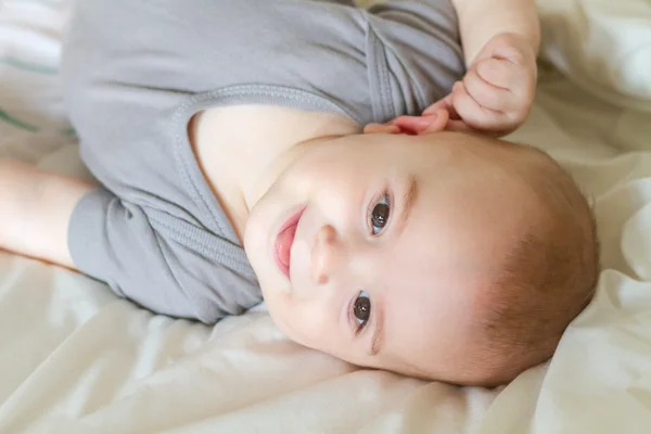 Baby laying on white sheets in bed — Stock Photo, Image
