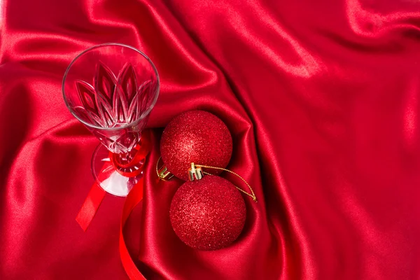 Baldes de Natal vermelho e taça de champanhe em um pano de seda vermelha — Fotografia de Stock