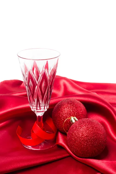 Rote Christbaumkugeln und Champagnerglas auf rotem Seidentuch — Stockfoto