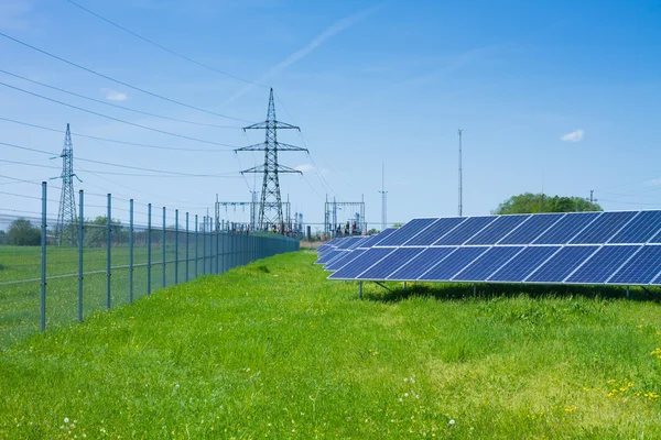 Solar panel against high voltage tower — Stock Photo, Image