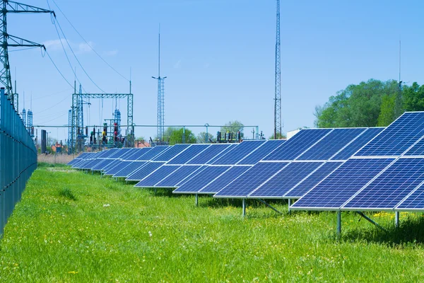 Solar panel against high voltage tower — Stock Photo, Image