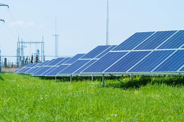 Solar panel against high voltage tower — Stock Photo, Image