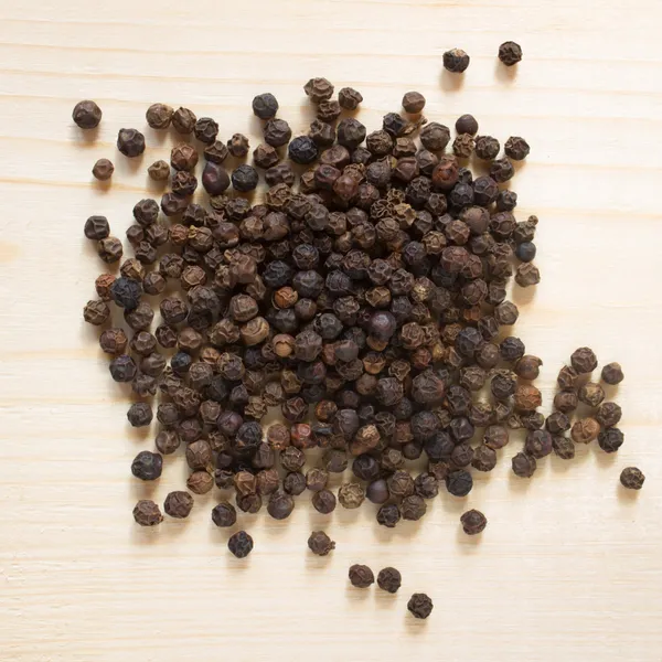 Black pepper on wooden background - top view — Stock Photo, Image