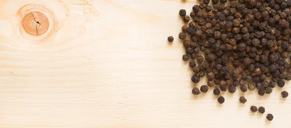 Black pepper on wooden background - top view — Stock Photo, Image