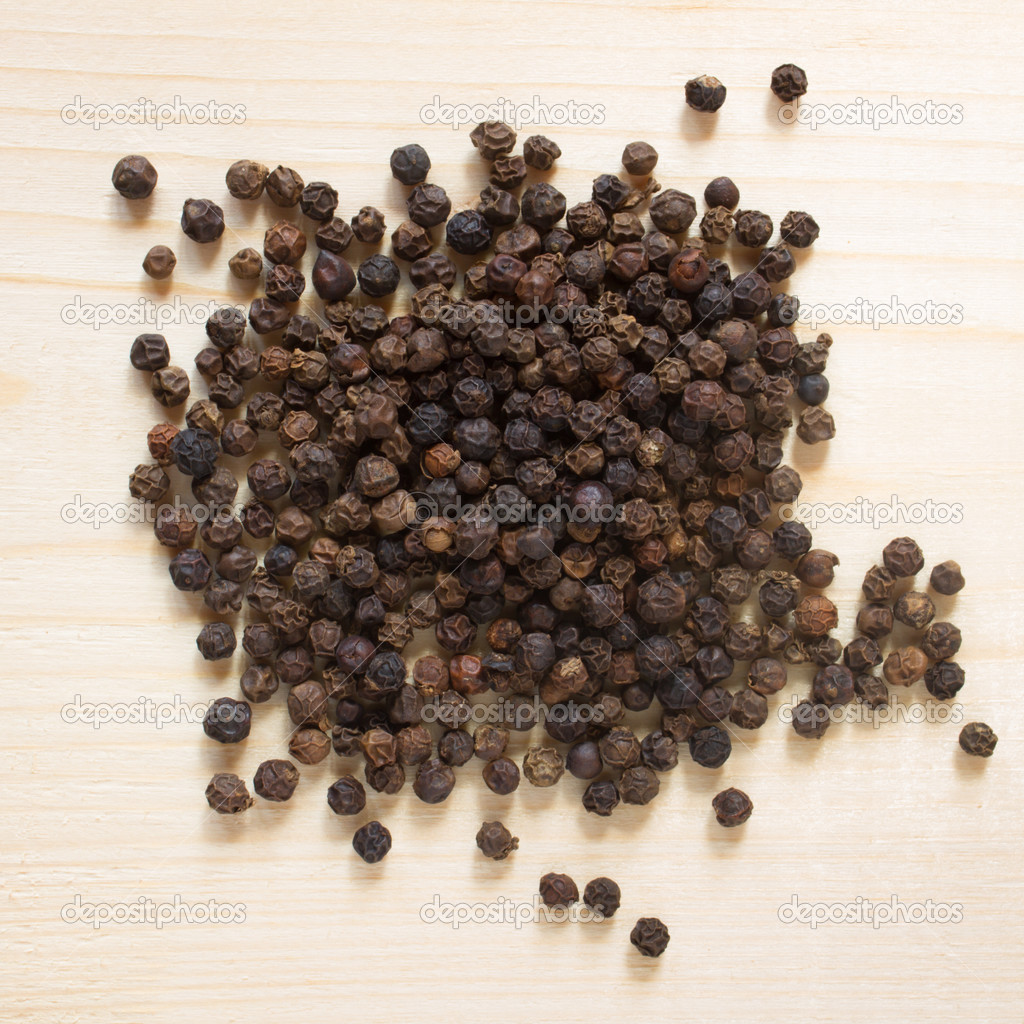 Black pepper on wooden background - top view