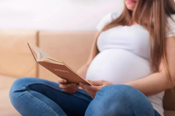 Schwangere liest auf der Couch — Stockfoto