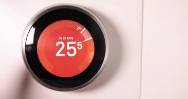 Celsios ölçeğinde akıllı termostatın sıcaklığını yavaş çekimde düşüren bir kişi