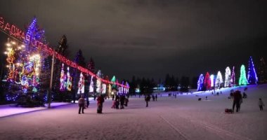 Calgary, Alberta, Kanada. 22 Aralık 2021. Lions Işık Festivali 'nde kayak yapan ve kızak kayan insanların panoramik görüntüsü Calgary' de bir Noel Işıkları gösterisi