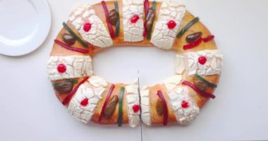 A person cutting a Rosca de Reyes - Three Kings Bread on a white table