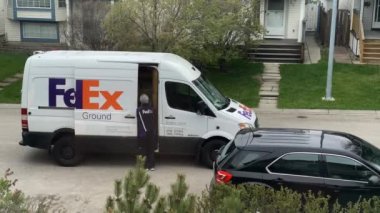 Calgary, Alberta, Kanada. 20 Mayıs 2022. Bir Fedex teslimatçısı varış noktasına bir paket götürüyor..